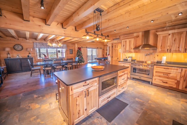 kitchen featuring hanging light fixtures, stainless steel appliances, a center island, beam ceiling, and wall chimney range hood