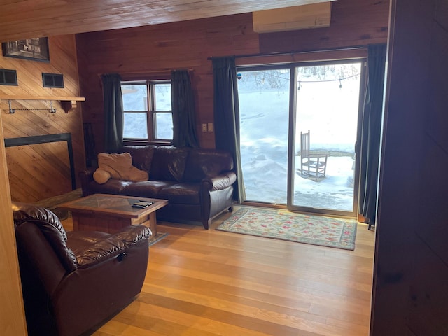 living room with wooden walls, hardwood / wood-style floors, a wealth of natural light, and a wall mounted AC