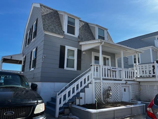 view of front of property with a shingled roof, stairs, a porch, and a gambrel roof