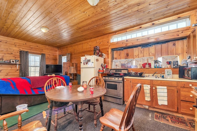 203 Kingston Rd, Danville, NH 03819 - kitchen featuring gas stove, freestanding refrigerator, wood walls, black microwave, and brown cabinets