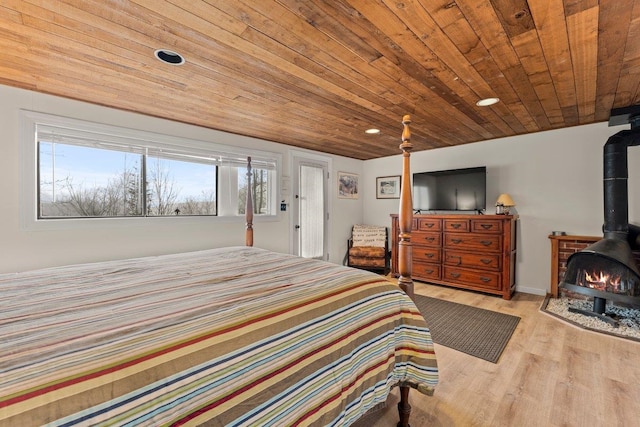 bedroom featuring light wood-type flooring, a wood stove, and wood ceiling