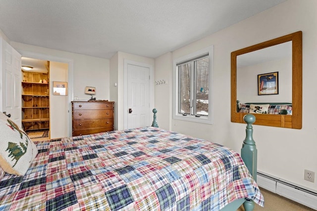 bedroom featuring baseboard heating, carpet floors, and a textured ceiling