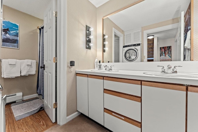 bathroom featuring baseboard heating, hardwood / wood-style floors, vanity, and washer / dryer