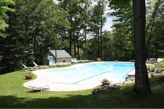 view of swimming pool featuring an outdoor structure and a lawn