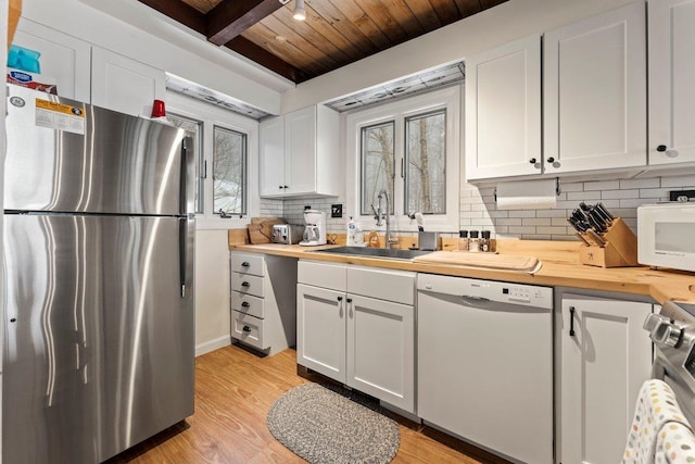 kitchen with wood counters, sink, white cabinetry, and stainless steel appliances