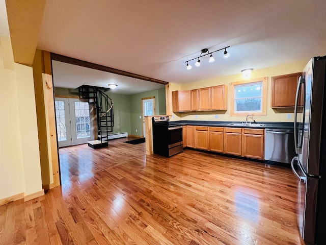 kitchen featuring a baseboard heating unit, appliances with stainless steel finishes, light hardwood / wood-style floors, rail lighting, and sink