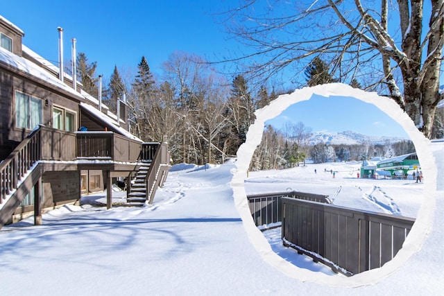 yard covered in snow featuring a deck with mountain view