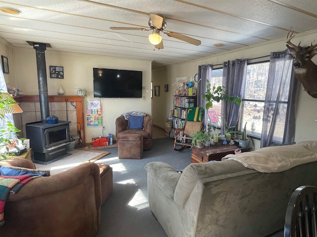 carpeted living room with ceiling fan, a wood stove, and a textured ceiling