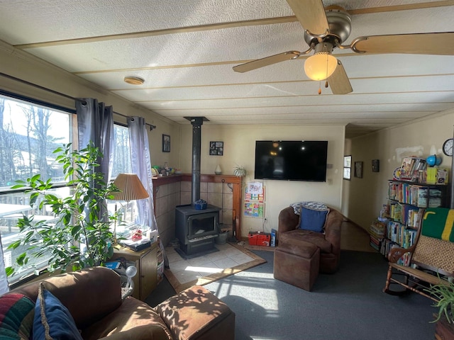 living area featuring a wood stove, ceiling fan, and a textured ceiling