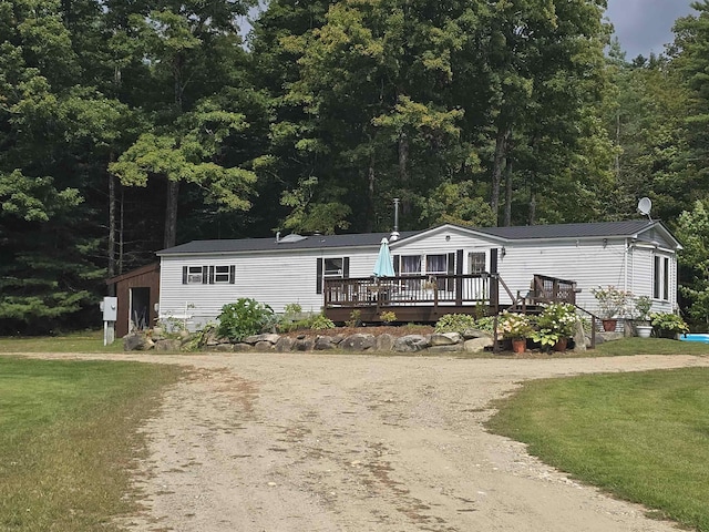 manufactured / mobile home featuring driveway, a wooden deck, metal roof, and a front yard