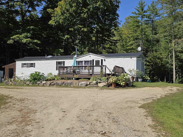 view of front of home with a deck, driveway, a standing seam roof, and metal roof