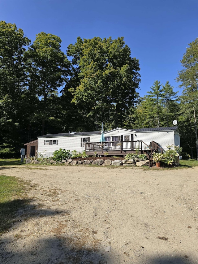 exterior space with a wooden deck and dirt driveway