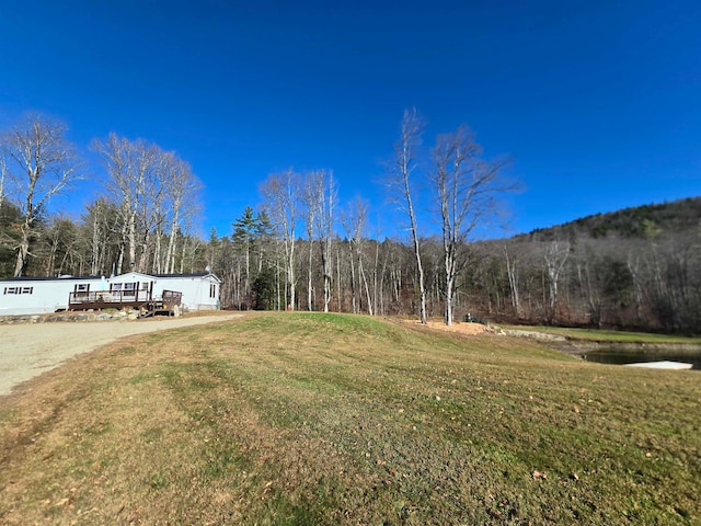 view of yard with a wooded view and a wooden deck