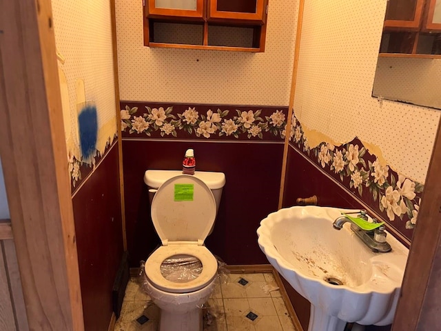 bathroom with toilet, tile flooring, and sink