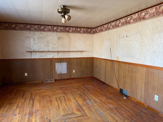 unfurnished room featuring dark parquet flooring and wood walls