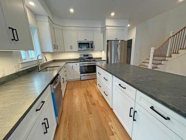 kitchen featuring sink, white cabinets, appliances with stainless steel finishes, and light hardwood / wood-style floors