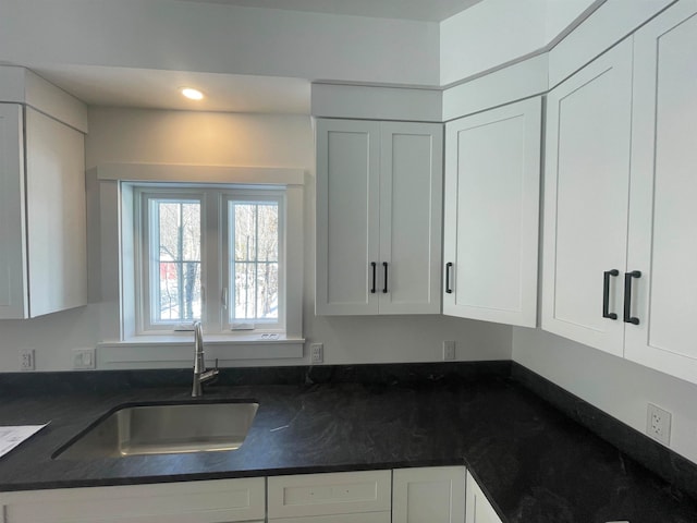 kitchen featuring sink, white cabinets, and dark stone counters