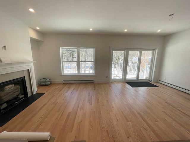 unfurnished living room featuring light wood-type flooring and a baseboard heating unit