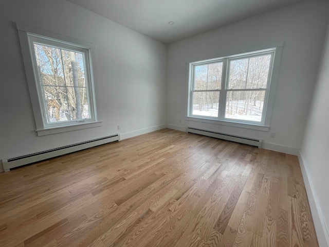 empty room featuring light hardwood / wood-style floors, a wealth of natural light, and baseboard heating