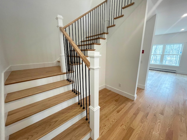 stairway featuring hardwood / wood-style floors and baseboard heating