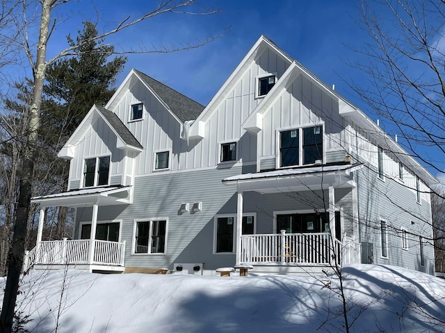 snow covered house featuring covered porch