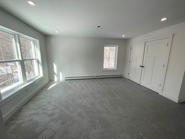 unfurnished bedroom featuring a baseboard heating unit and dark carpet