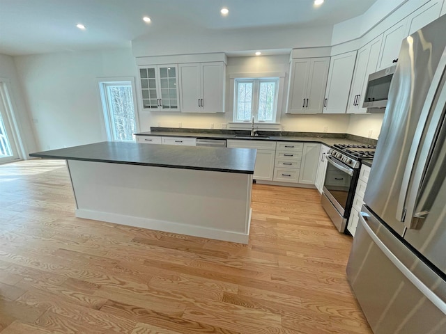 kitchen with light wood-type flooring, white cabinetry, appliances with stainless steel finishes, sink, and a center island