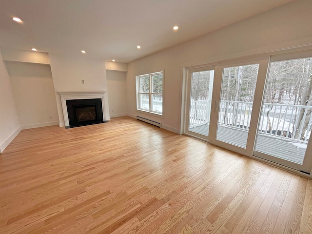 unfurnished living room featuring a baseboard heating unit and light hardwood / wood-style flooring