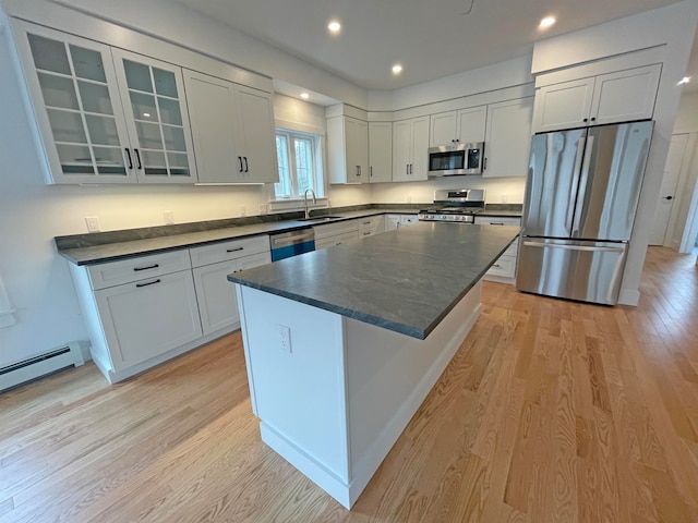 kitchen with light hardwood / wood-style flooring, a kitchen island, white cabinetry, appliances with stainless steel finishes, and sink