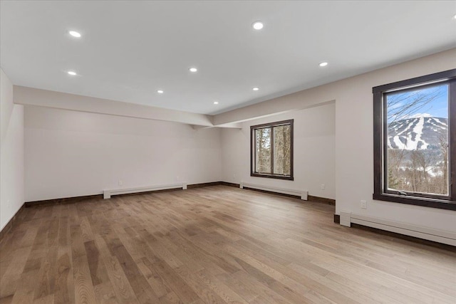 empty room with light hardwood / wood-style floors, a healthy amount of sunlight, and a baseboard radiator