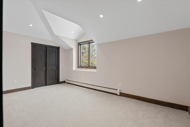 unfurnished bedroom with baseboard heating, lofted ceiling, and carpet flooring