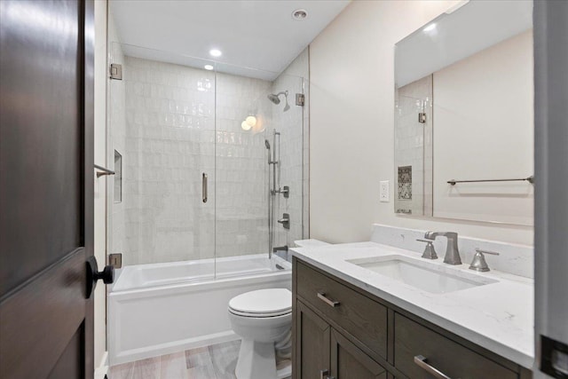 full bathroom featuring vanity, combined bath / shower with glass door, hardwood / wood-style flooring, and toilet