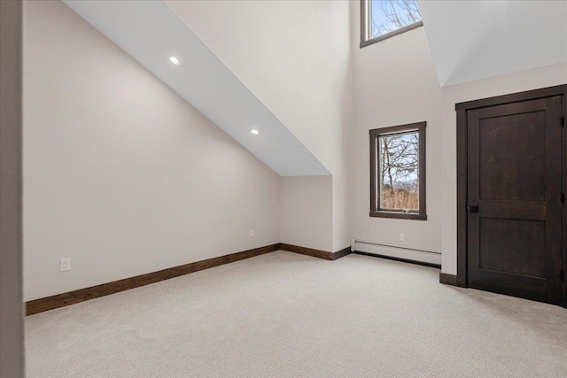 bonus room featuring baseboard heating, light carpet, and a towering ceiling