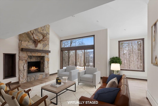 living room featuring light hardwood / wood-style floors, a fireplace, high vaulted ceiling, and a baseboard radiator