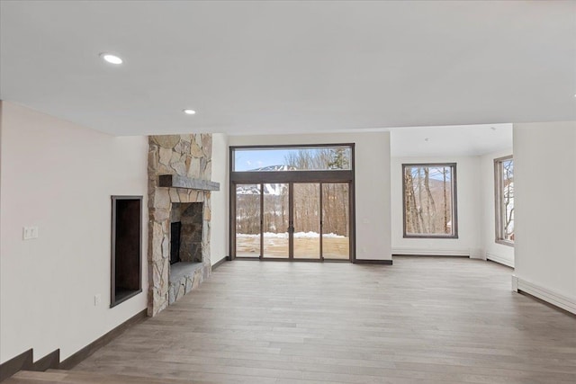 unfurnished living room featuring light hardwood / wood-style flooring, a healthy amount of sunlight, and a fireplace