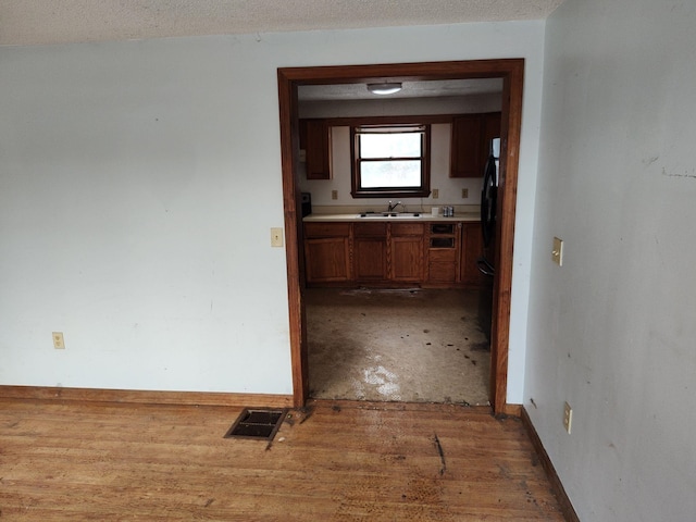 hallway with a textured ceiling, dark wood-type flooring, and sink