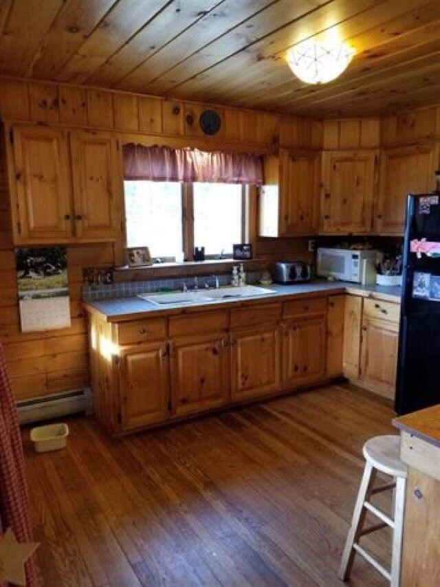 17 Tracy Hill Rd, Northfield, VT 05663 - kitchen with freestanding refrigerator, wood ceiling, baseboard heating, white microwave, and dark wood-style flooring