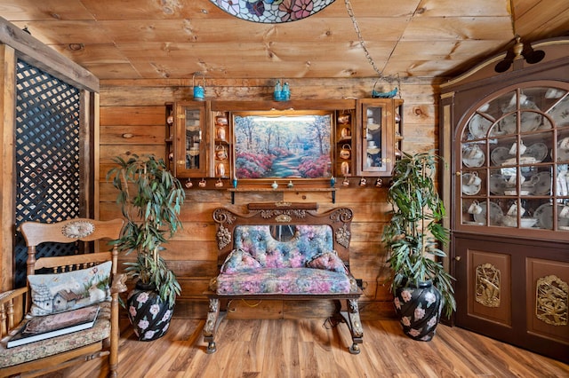 living area with light hardwood / wood-style flooring, wood ceiling, and wooden walls