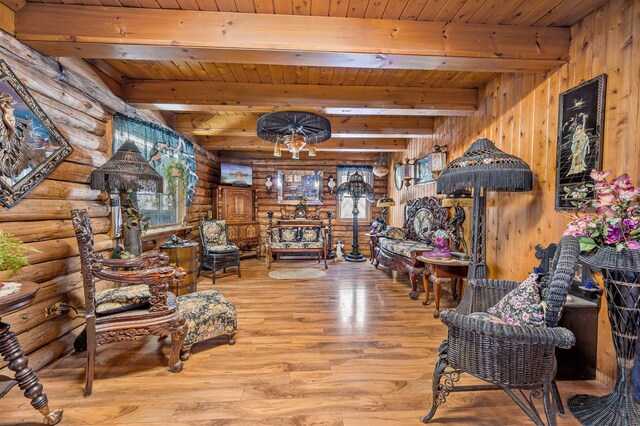 living room featuring beam ceiling, rustic walls, and light hardwood / wood-style flooring