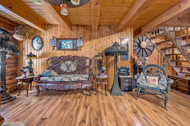 sitting room featuring wooden walls, light wood-type flooring, beamed ceiling, and wood ceiling