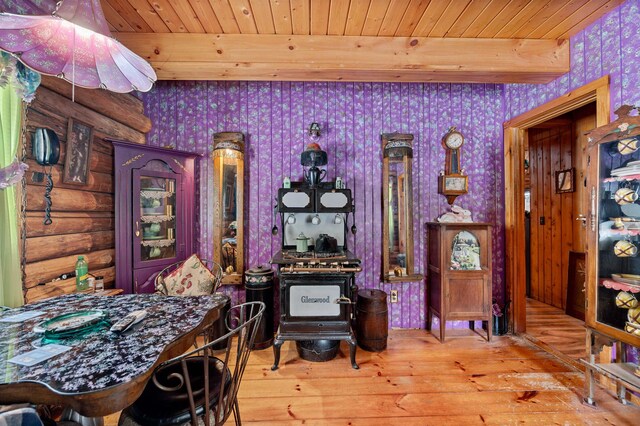 dining area featuring rustic walls, beamed ceiling, wooden ceiling, and light wood-type flooring