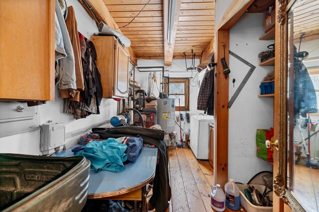 kitchen featuring gas water heater, light hardwood / wood-style flooring, washing machine and clothes dryer, and beam ceiling