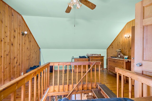 hallway with wood-type flooring, wood walls, and lofted ceiling