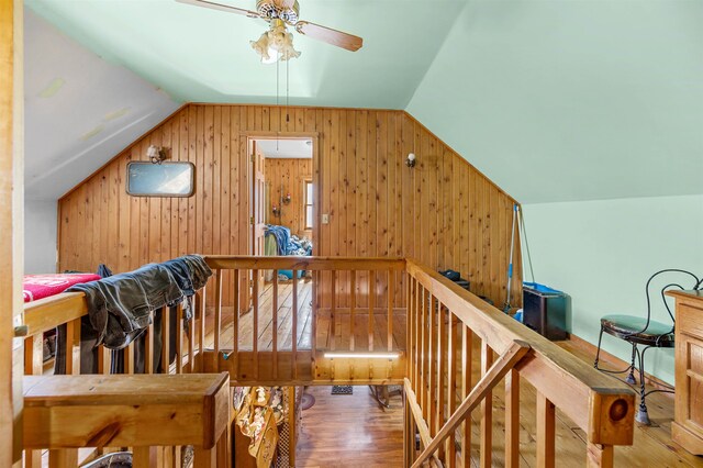 stairway featuring lofted ceiling, wooden walls, ceiling fan, and hardwood / wood-style flooring