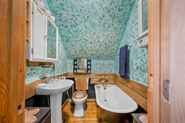 bathroom featuring a bath, toilet, hardwood / wood-style flooring, and vaulted ceiling