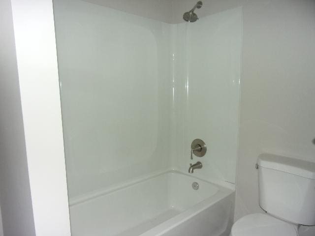 bathroom featuring bathtub / shower combination and toilet