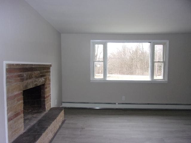 unfurnished living room with dark hardwood / wood-style flooring, a baseboard radiator, and a fireplace