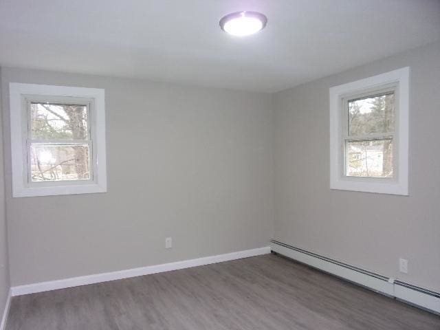 empty room with dark hardwood / wood-style floors and baseboard heating