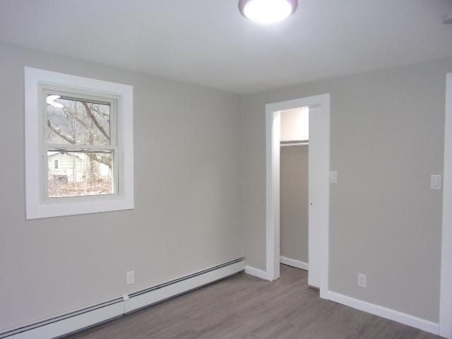 spare room featuring baseboard heating and dark wood-type flooring