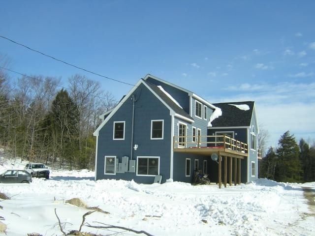 snow covered rear of property featuring a wooden deck